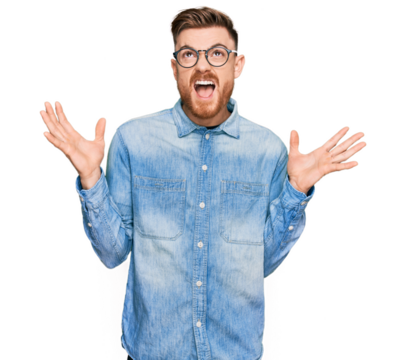 Young redhead man wearing casual denim shirt crazy and mad shouting and yelling with aggressive expression and arms raised. frustration concept.