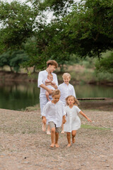 children, brothers and sisters walk near the lake in the summer, a large family