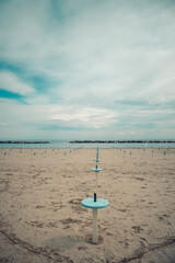 Romagna or Riviera Romagnola beach, off season mood. Before season starts in april or may, or october. Liminal spaces, slight melancholy feeling, uncertain weather, damp sand.