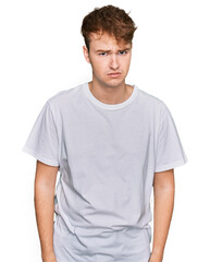 Young caucasian man wearing casual white t shirt skeptic and nervous, frowning upset because of problem. negative person.