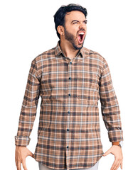 Fototapeta premium Young hispanic man wearing casual clothes angry and mad screaming frustrated and furious, shouting with anger. rage and aggressive concept.