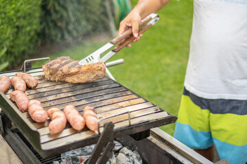 Man turning meat on barbecue to cook it properly