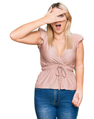 Fototapeta premium Young caucasian woman wearing casual clothes peeking in shock covering face and eyes with hand, looking through fingers with embarrassed expression.