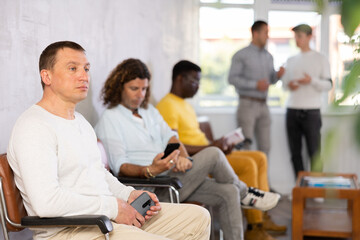 Man sitting in lobby of job center or employment office, waiting for interview or conversation with...