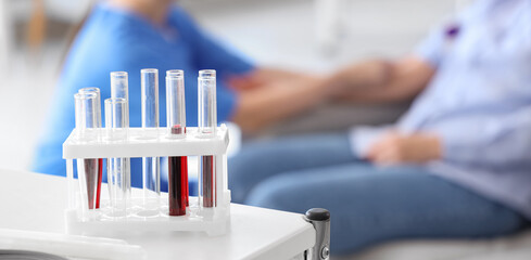 Test tubes with blood on table in clinic, closeup - obrazy, fototapety, plakaty