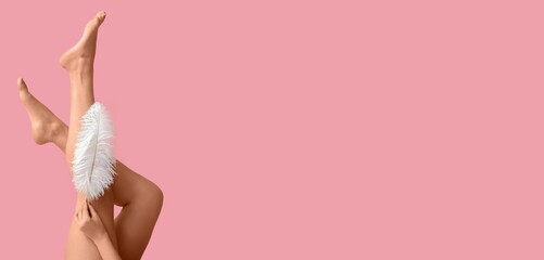 Legs of young woman with soft feather on pink background with space for text. Epilation concept