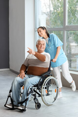 Senior man in wheelchair and nurse at hospital