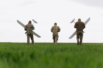 Soldiers of the modern army walk holding unmanned aerial vehicles in their hands. Soldiers on a...