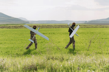 two soldiers are holding drones. soldiers use drones. modern technological warfare. reconnaissance aircraft