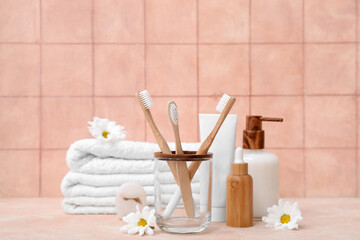 Set of bath supplies and flowers on table against color tile wall