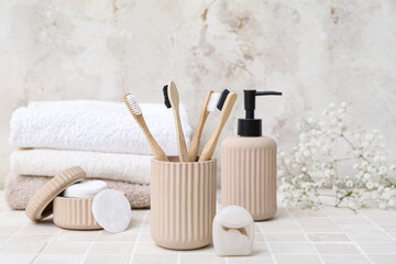 Set of bath supplies with bamboo toothbrushes on light tile table