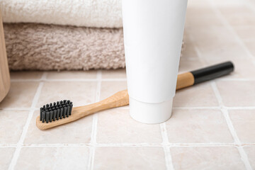 Bamboo toothbrush, paste and towels on light tile table, closeup