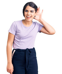 Obraz premium Brunette teenager girl wearing casual clothes smiling with hand over ear listening an hearing to rumor or gossip. deafness concept.