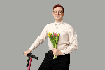 Young man with modern electric kick scooter and bouquet of beautiful tulips on grey background