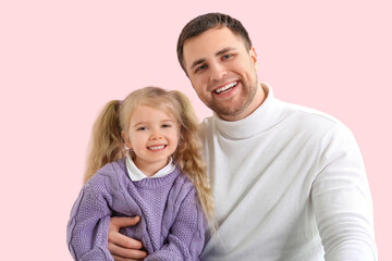 Happy father and his cute little daughter on pink background