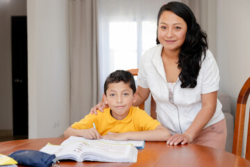 Hispanic mom and son studying at home - happy child doing his homework. teacher with her student - home education