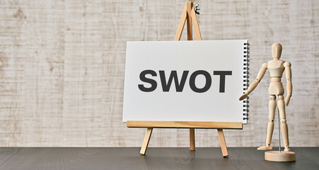 There is notebook with the word SWOT. It is an abbreviation for strengths, weaknesses, opportunities, threats as eye-catching image.