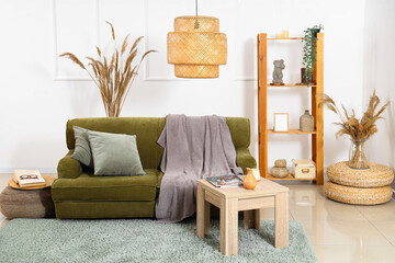 Interior of cozy living room with green sofa, table and pampas grass