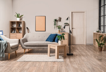 Interior of light living room with grey sofa, table and plants