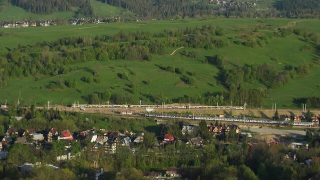 An electric train travelling through the city, aerial view. A caterpillar from the train. 