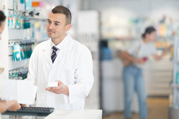 Man pharmacist helps woman buy prescription at the pharmacy