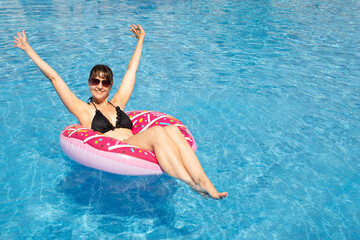 A cheerful  woman in the pool on a sunny day. Beautiful woman having fun in the pool. summer vacation. blue background, sea background