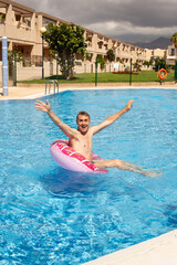 Naklejka premium man swims and has fun near a beautiful pool at a resort during vacation. blue background, sea background