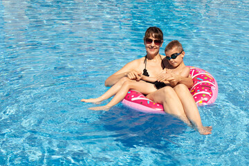 happy parents with children playing and having fun in the pool during the holidays. family vacation...