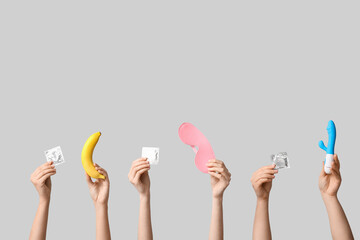Female hands with condoms, sex toys and banana on grey background