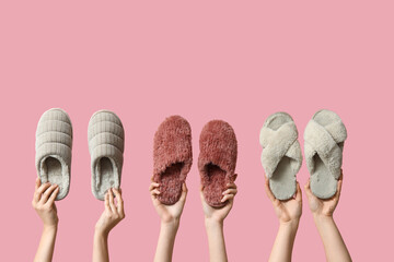 Female hands holding different women's slippers on pink background