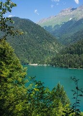 Bright turquoise lake Ritsa in Abkhazia among green hills on a sunny summer day