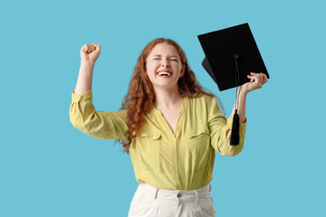 Happy female student with graduation hat showing yes gesture on blue background