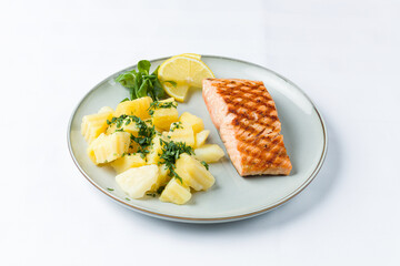 Grilled salmon with boiled potatoes, chopped parsley and lemon slices. 