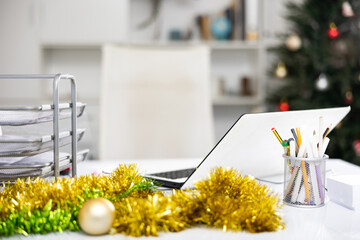 Laptop and christmas tinsel on table in modern office. Office workplace