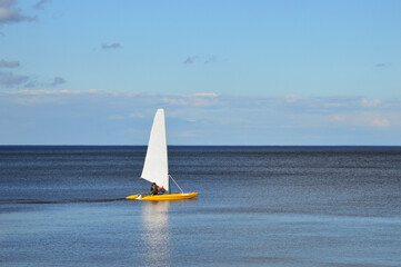 Catamaran with sail on lake.