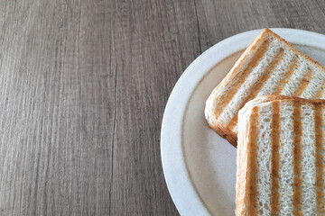 Quick breakfast snack. Two toasts on a plate on a gray wooden table. Preparing a simple meal sandwich at home in kitchen. Culinary template with space to insert text.