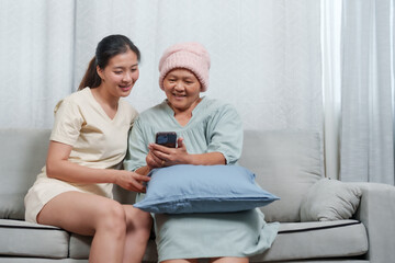 Contentment on faces of elder wearing soft pink beanie and younger woman as they view phone....