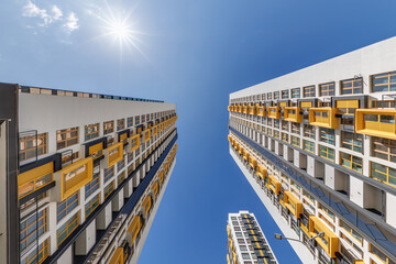 view from below into blue sky with clouds of large modern skyscraper residential complex