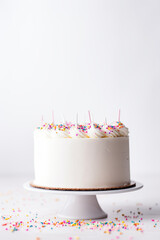 Simple vanilla white cake on a solid white background with empty space and some sprinkles