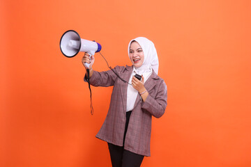Cheerful young indonesia girl in hijab facing right sideways candid shouting using mic holding...