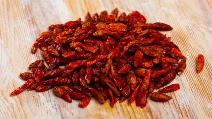 Pile of dried red cayenne peppers on wooden background. Organic spicy seasoning