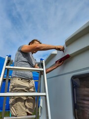 An experienced handyman is meticulously repairing a roof vent on a recreational vehicle using a...
