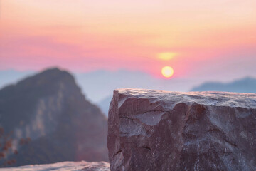 Sunset view with large rock surface in the foreground and mountains background. High quality photo