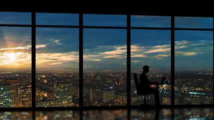 Business person working late in office overlooking city
