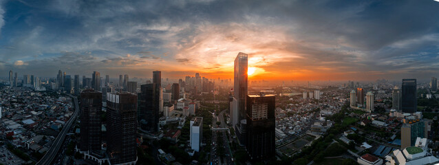 Wide-angle panoramic view of a bustling city skyline bathed in the golden hues of sunset