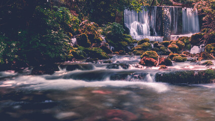 Tranquil waterfall cascading over mossy rocks in a serene forest setting