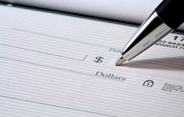 Detailed view of a hand filling out a check with a pen, focusing on the amount section