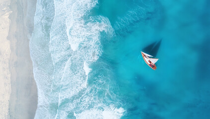 Aerial view of sailboat on turquoise ocean waves