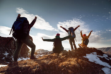 Triumphant hikers celebrating on mountain top at sunset