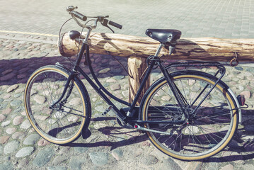 Retro Bicycle Standing In Empty Street Lighted With Beautiful Sunlight Glare. Vintage Effect Filter